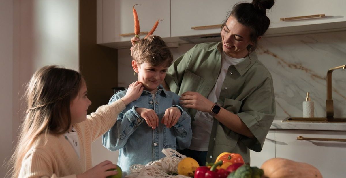 Mother and children have fun unpacking vegetables in the kitchen.