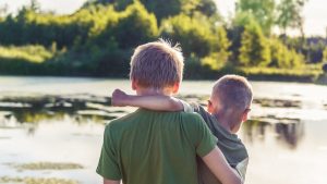 two brothers toghere are standing in front of a pond